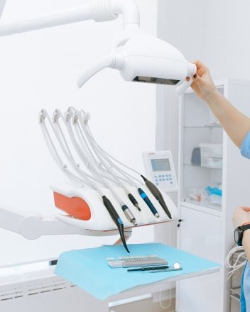 Equipo de odontología con varias piezas de mano dispuestas en una unidad, con un paño azul y herramientas adicionales sobre una mesa.